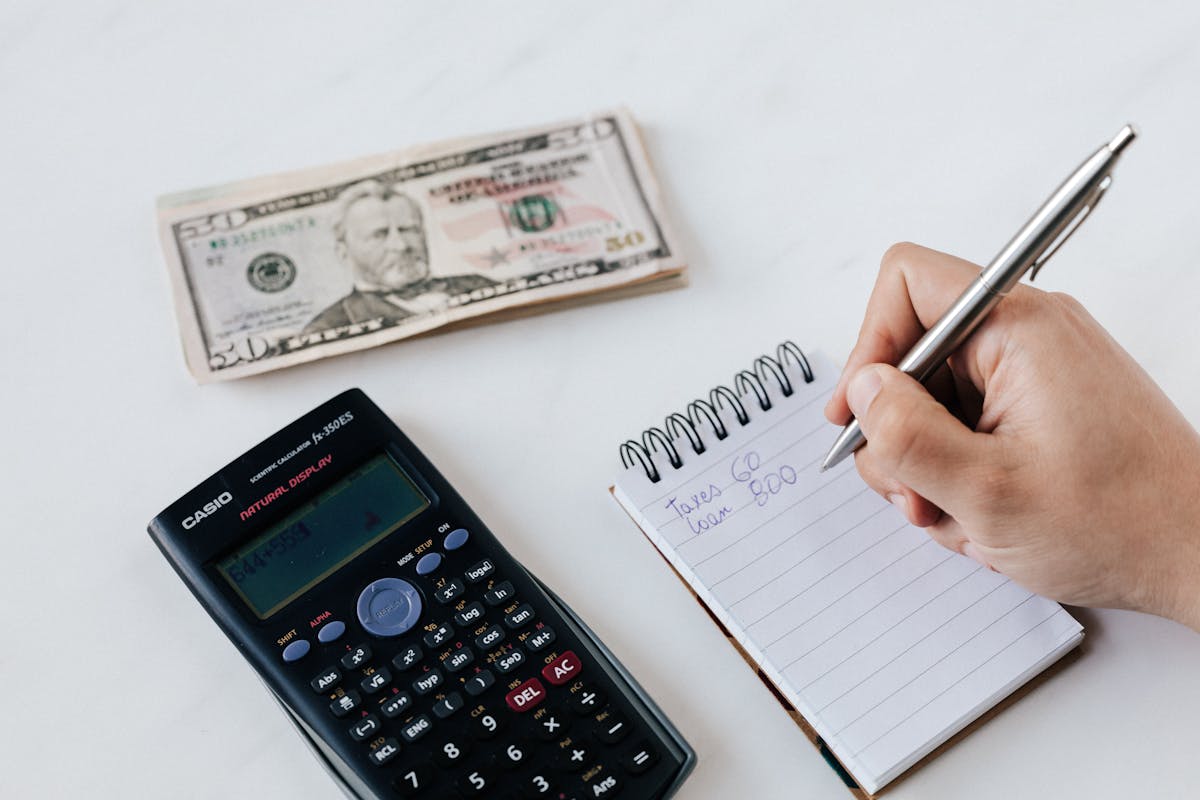 Finance broker Wollongong reviewing loan figures with a calculator, cash and notebook for an Illawarra borrower